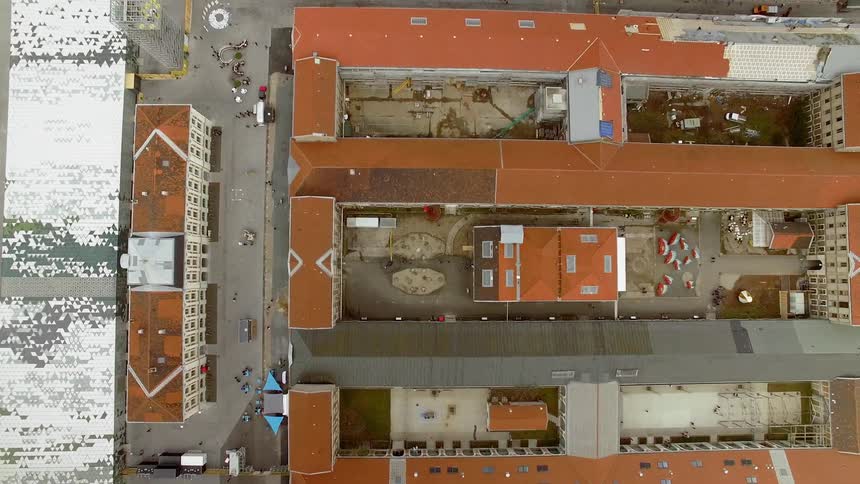 Multi storey buildings with mainly brown roofs organized in rectangles