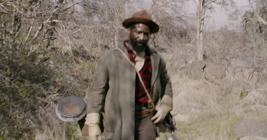 A man is hiking down a trail in the woods
