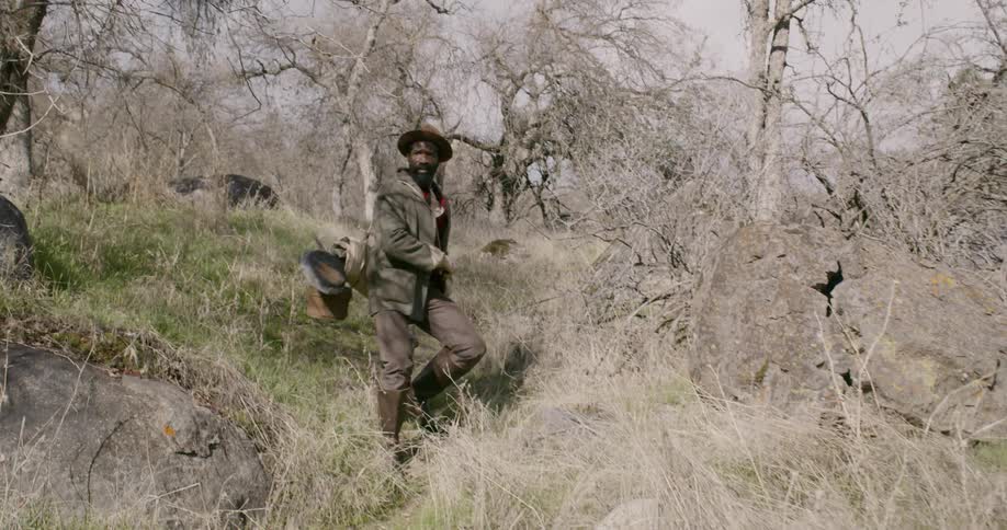 A man walking down a rocky hill surrounded by trees