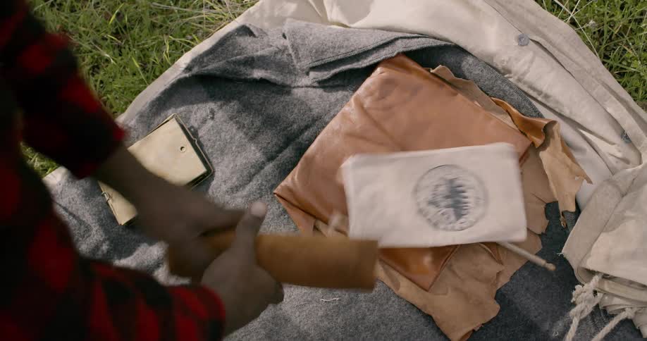 A man moving camping supplies on a blanket outside