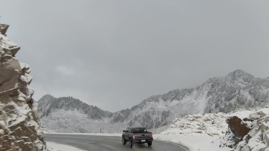 A car driving up a mountain road in the middle of the snow