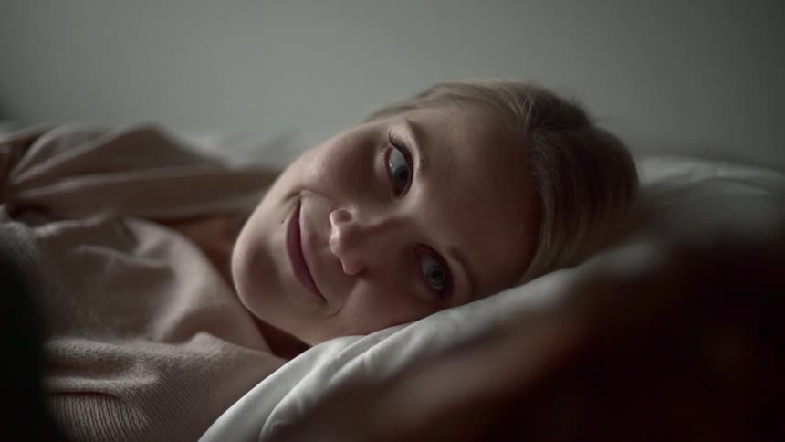 A woman smiling while laying on a bed and looking at a man laying next to her