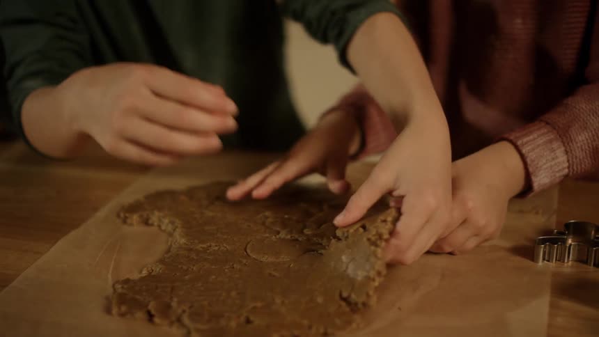 Two children handle cookie dough on a kitchen counter
