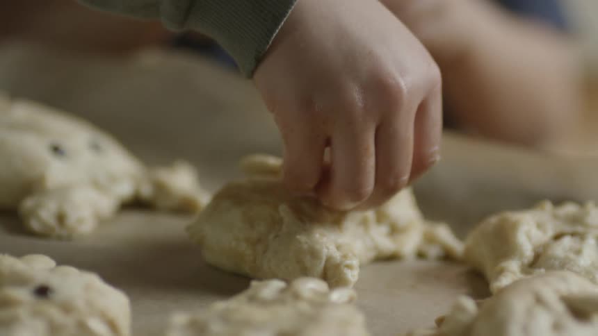 A child puts chocolate chips in dough