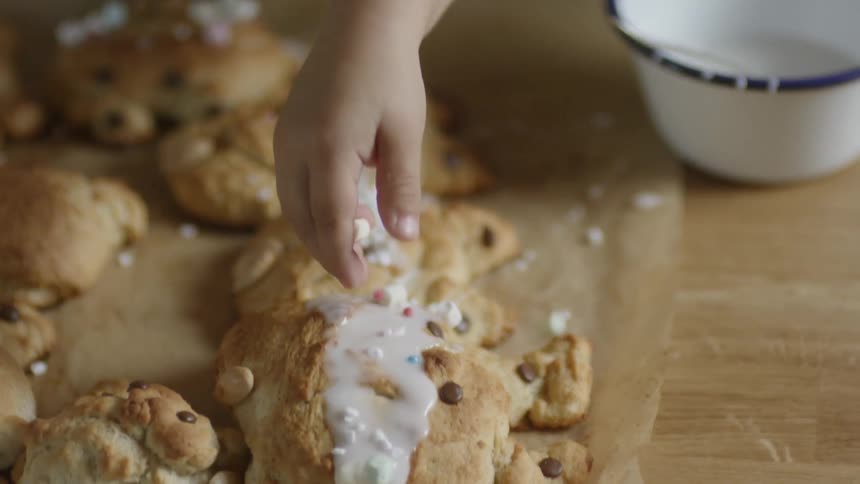 A child takes marshmallows out of a bowl and puts them on a treat