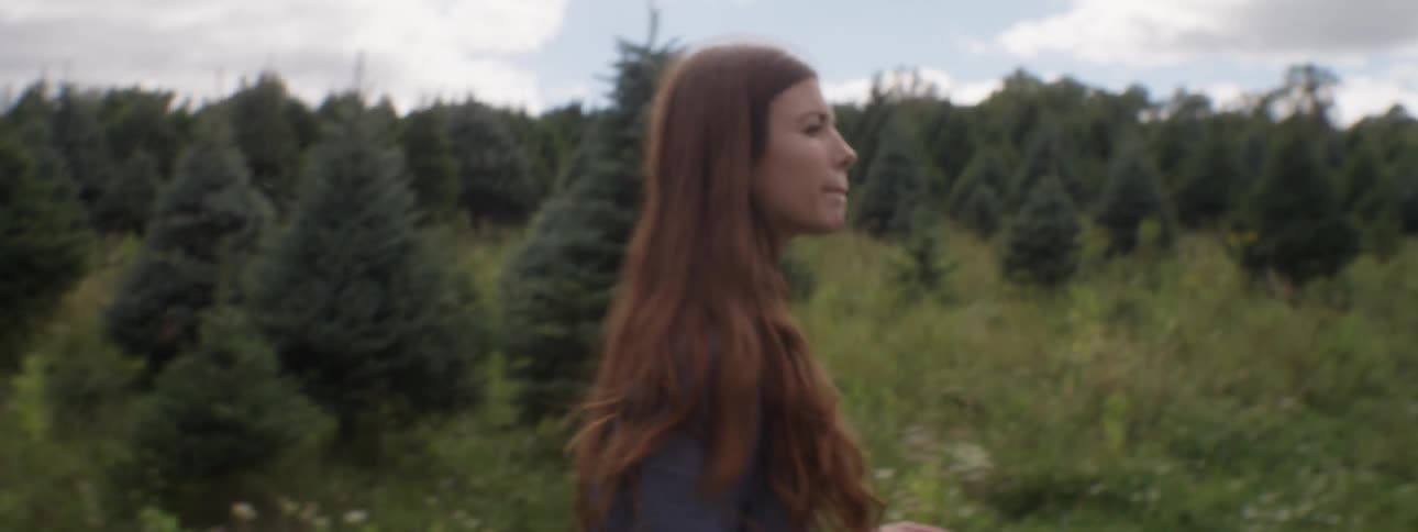 A woman walks through a forested area