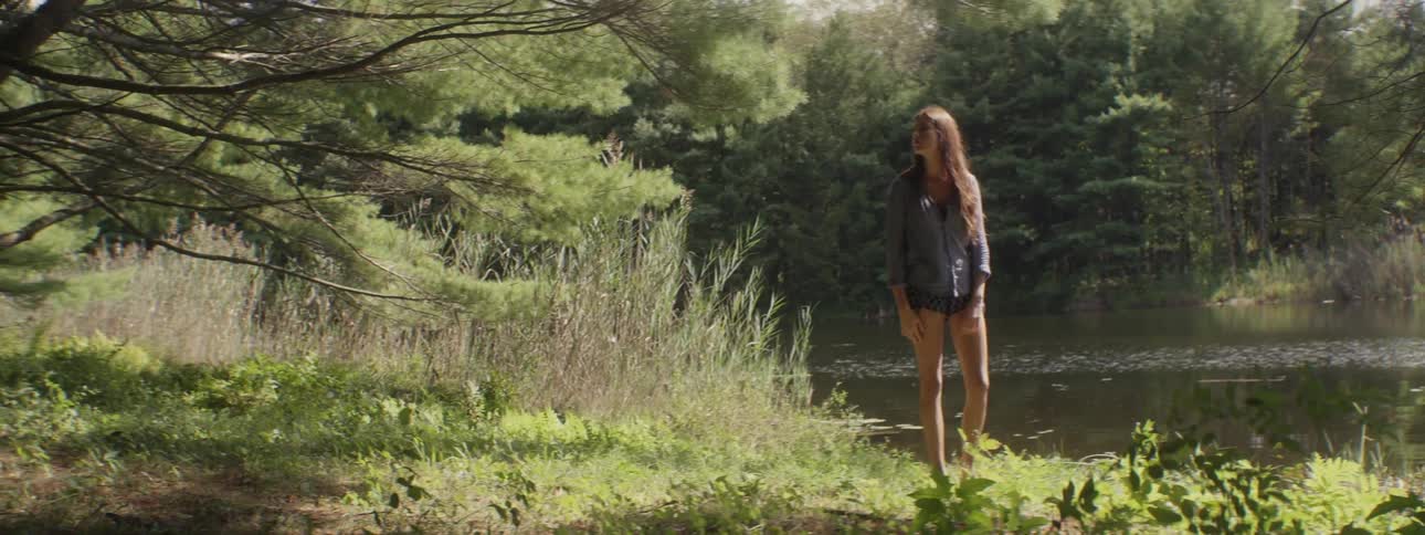 A woman stands near a river