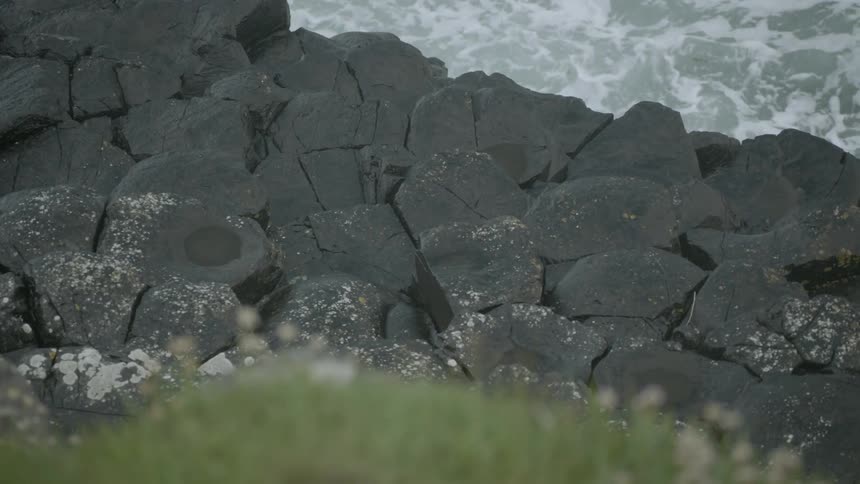 Ocean waves splash next to a rocky shoreline