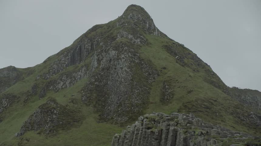 A grass covered mountain with hexagonal rocks