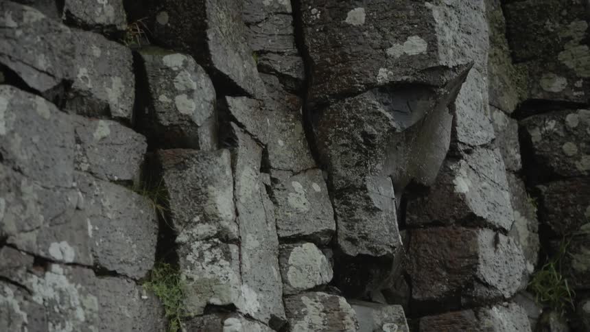 Rocks stones and boulders in a natural wall with grass and moss
