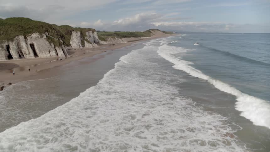 An aerial view of ocean waves flowing towards a shoreline