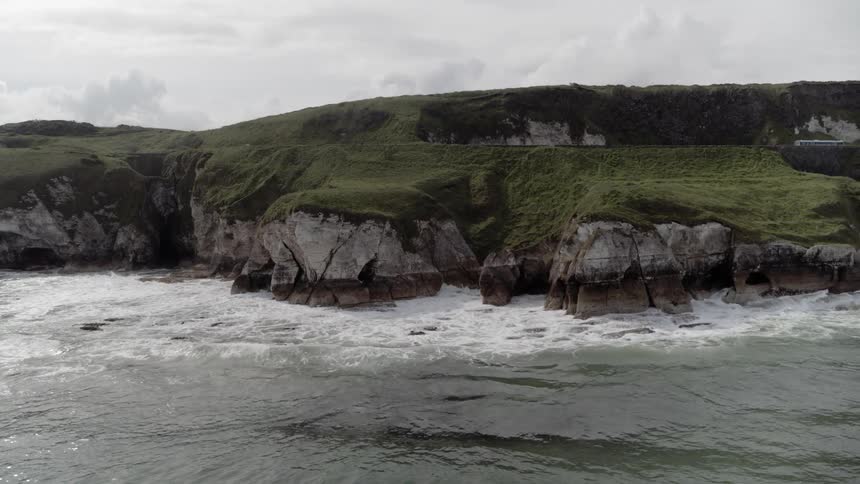 The sea crashing on the rocky coast near a road
