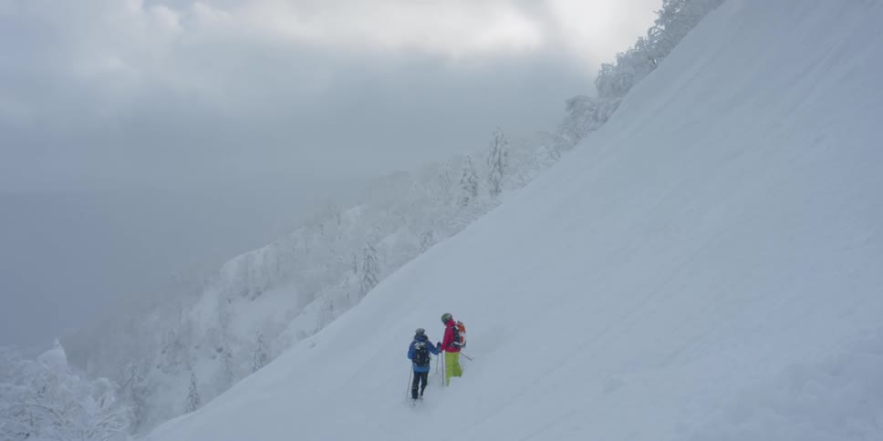 Skiers standing on a very steep snow covered slope