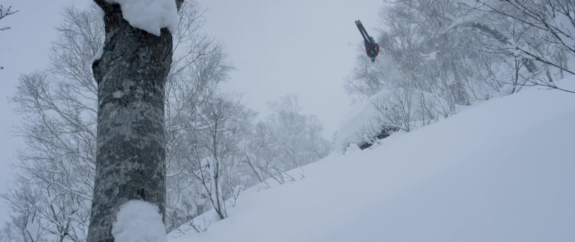 A skier jumps and flips and lands on a snow covered slope