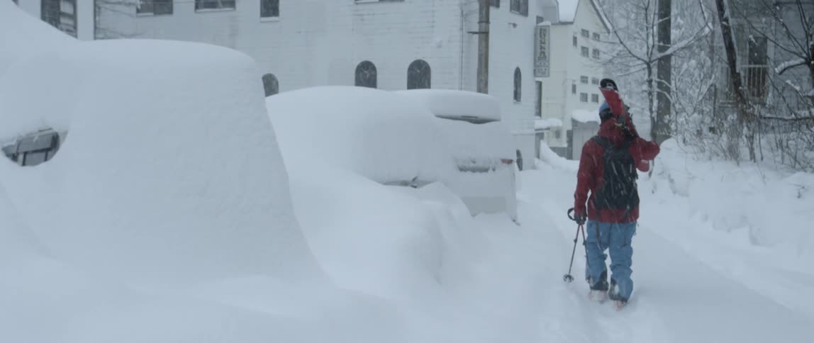 A man carries his ski equipment down a path
