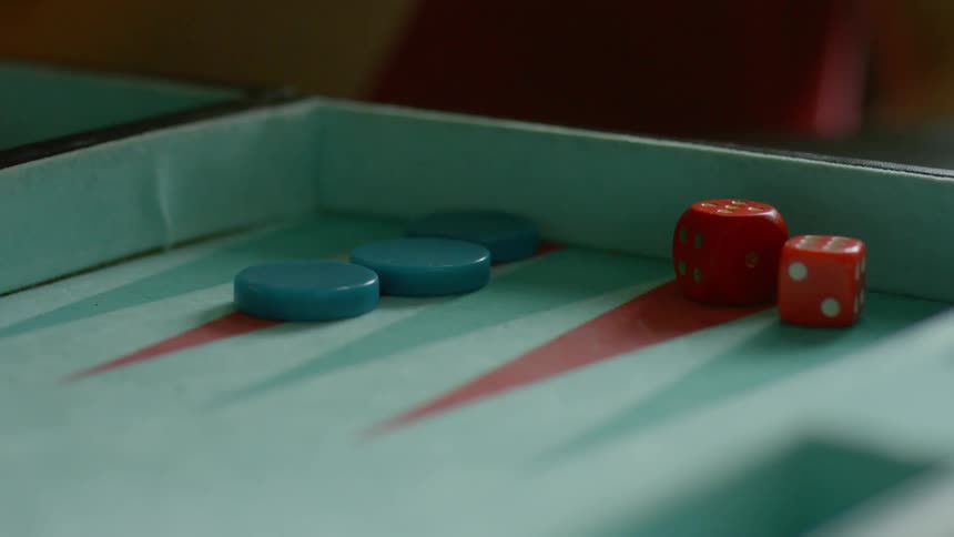 Person rolling dice on a backgammon board