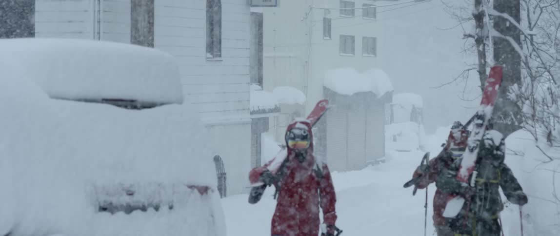 Slow reveal of skiers walking down a street
