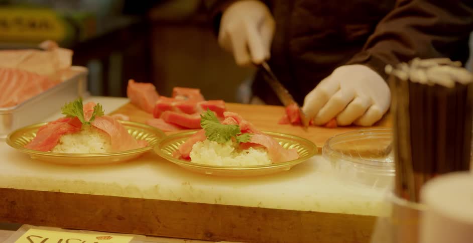 A chef slicing meat and preparing a sushi dish