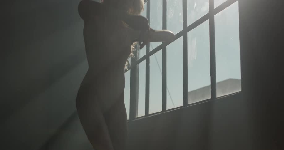 A woman in a bodysuit stretches against a georgian window letting in the morning sun
