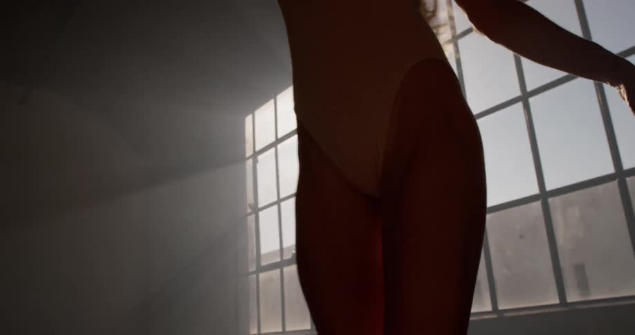 Dancer twirls in front of window in dark room