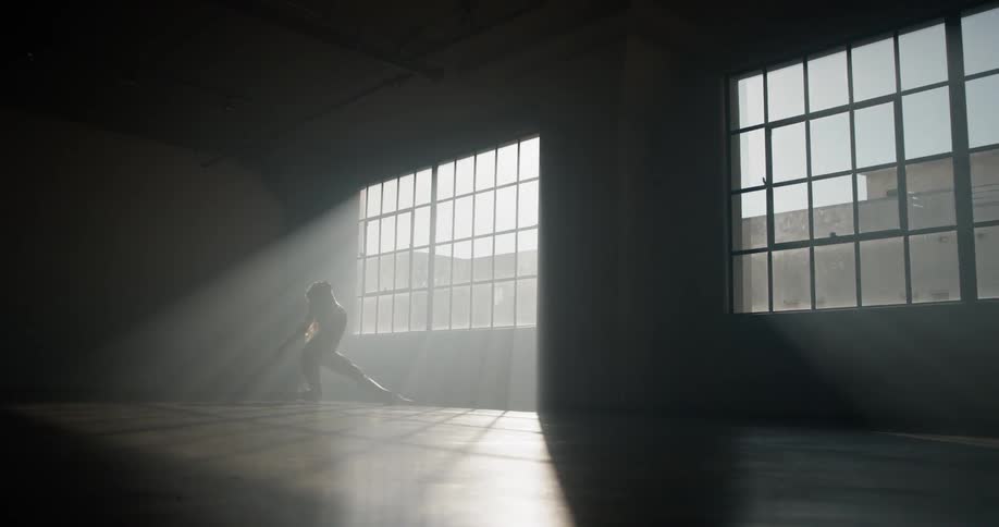 Woman ballet dancer dances in dimly lit room