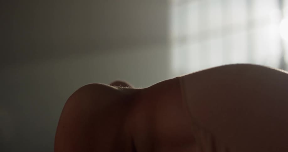 A female dancer leans back in front of a sunny window in a dance studio