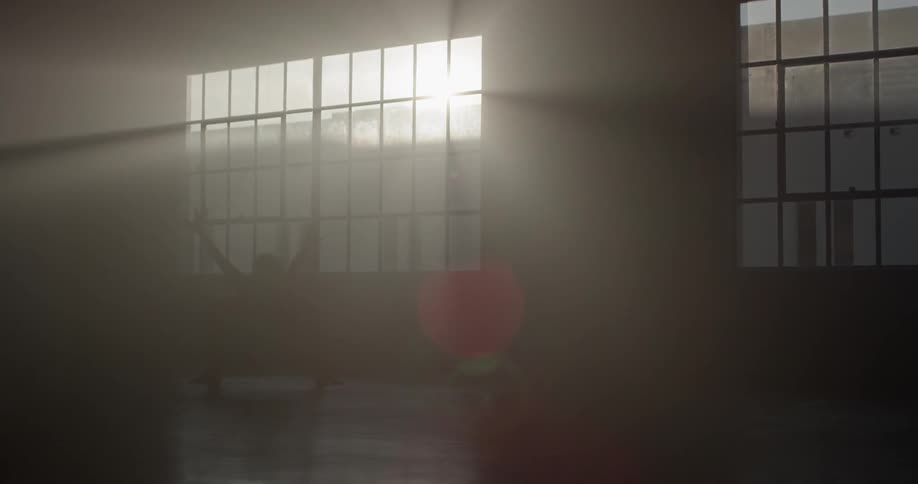 Woman practices ballet on a studio at sunset