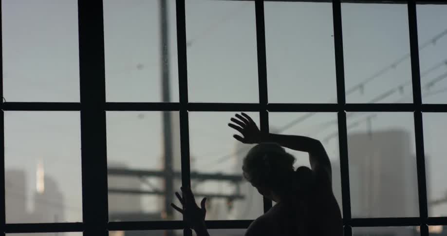 A woman dancing and stretching against a large loft window