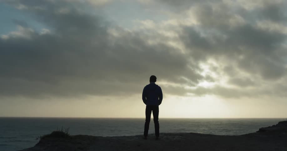Man stands looking out over the ocean