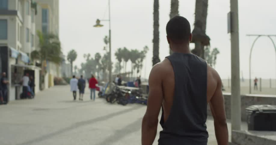 A man walks down a beachside sidewalk
