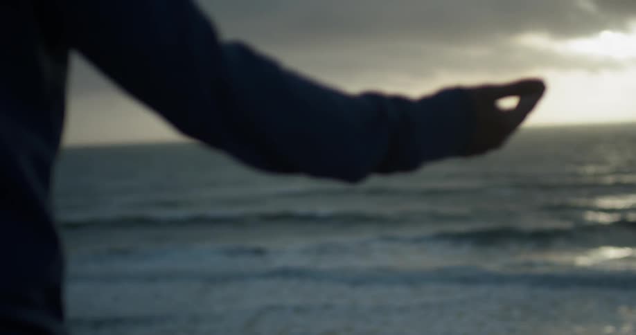 A person meditating while standing on a beach