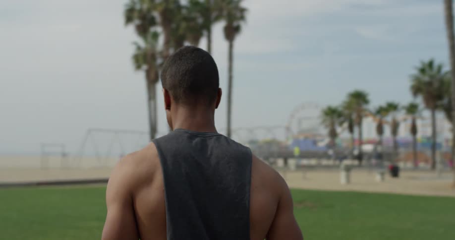 A man walks through grass toward a beach playground