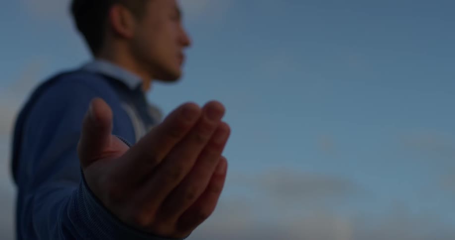 A person holds their hand out while standing outside