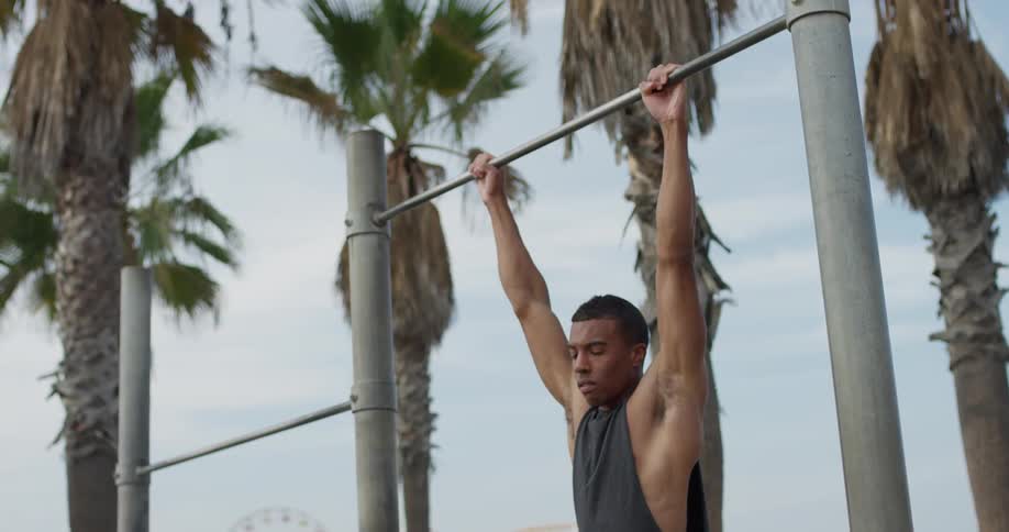 A young man does pull ups outside