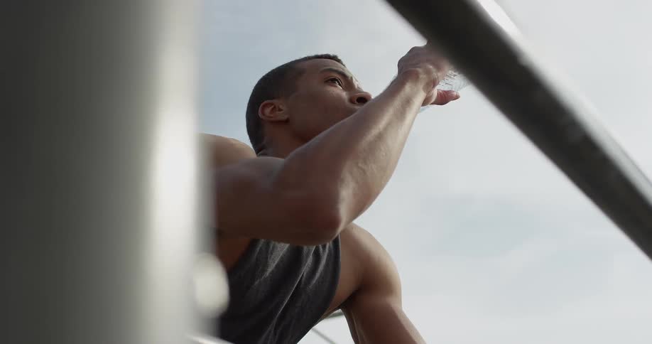 Man resting elbows on handrail drinking water