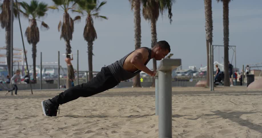 A young man does push ups in a park