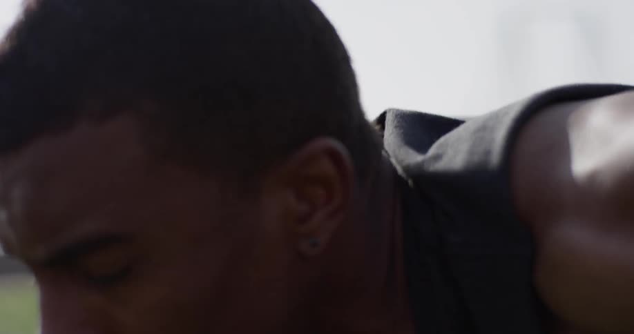 Black man wearing black tank top pushes up on the grass during daylight