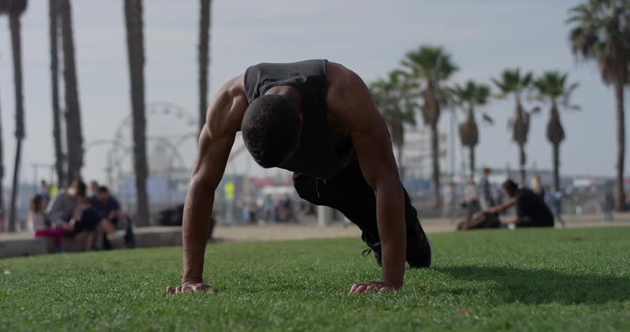 A man is doing push ups on the grass