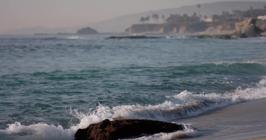 Ocean waves roll into shore and spread over the sand