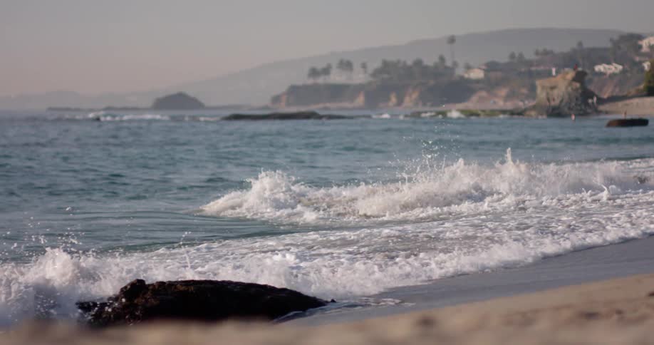 On a white sandy beach the waves come ashore sweeping all the sand away