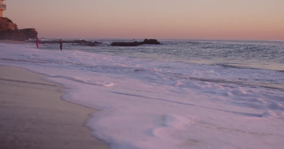 Waves rolling into a beach at sunset