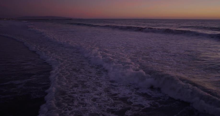 Ocean waves break and splash as they come to shore at sunset