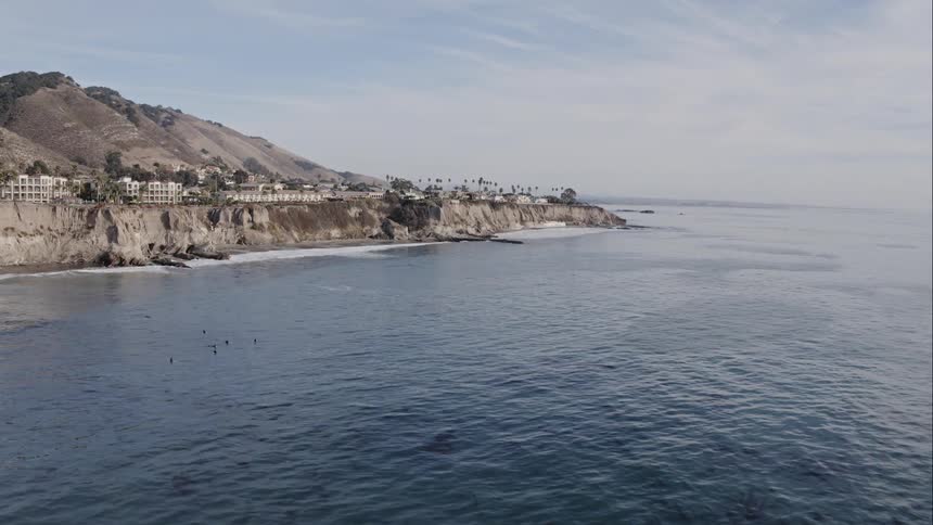 Buildings and palm trees on the cliffs above the ocean