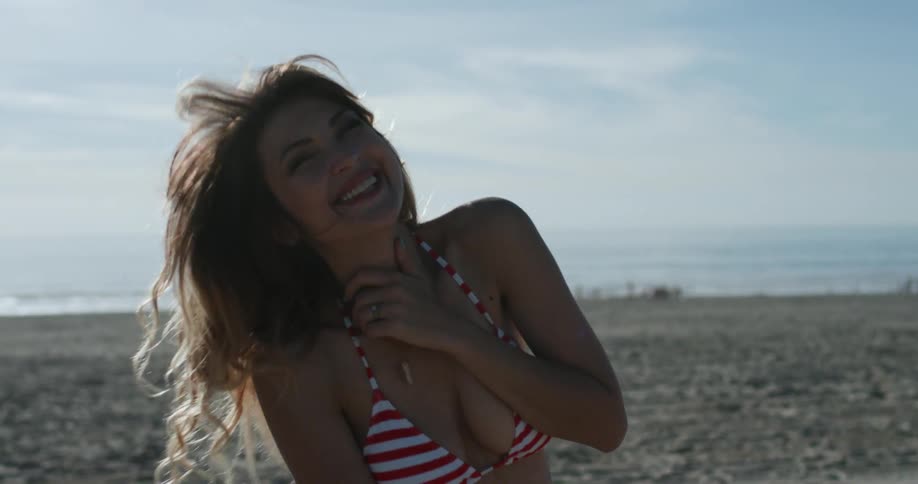 A young woman stands and laughs on the beach
