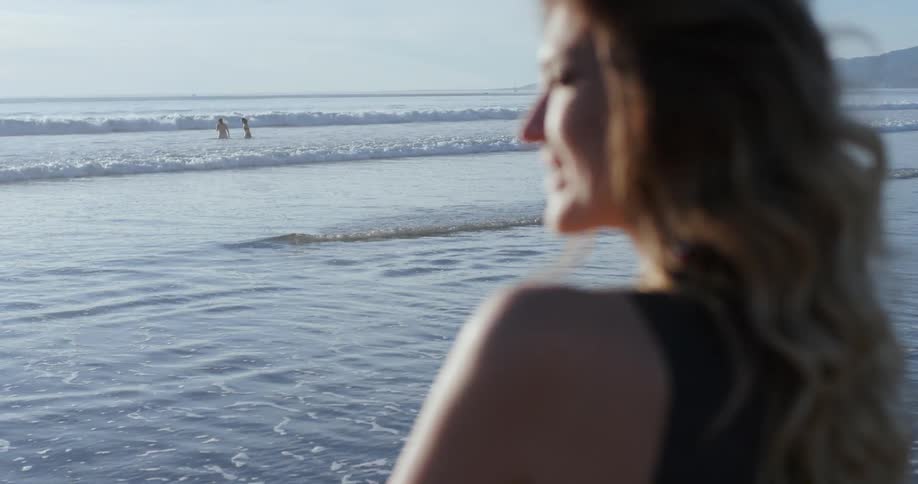 Woman stands on beach looking at sunrise