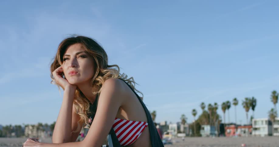 Woman sits on the beach gazing into the distance