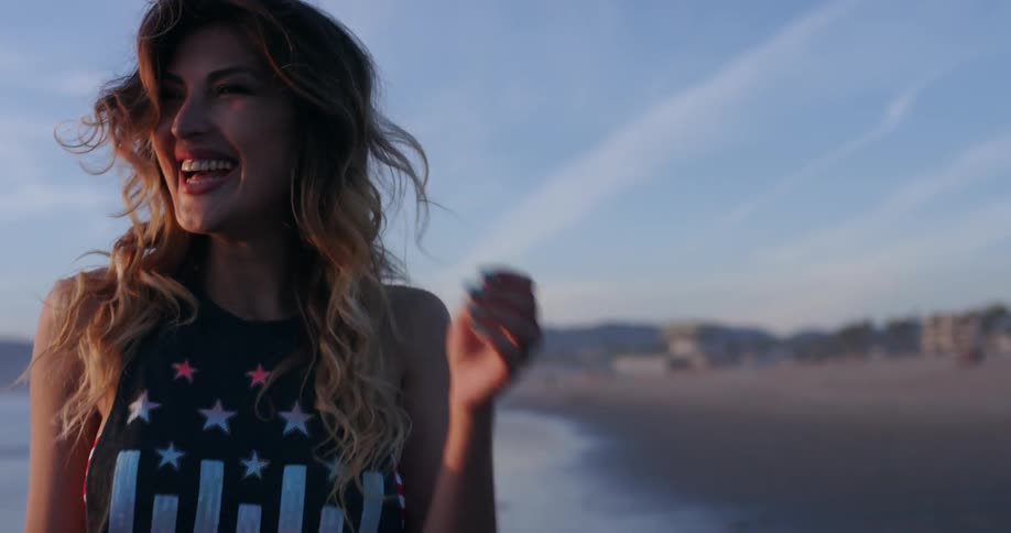 A woman throwing a rock in the beach and smiling
