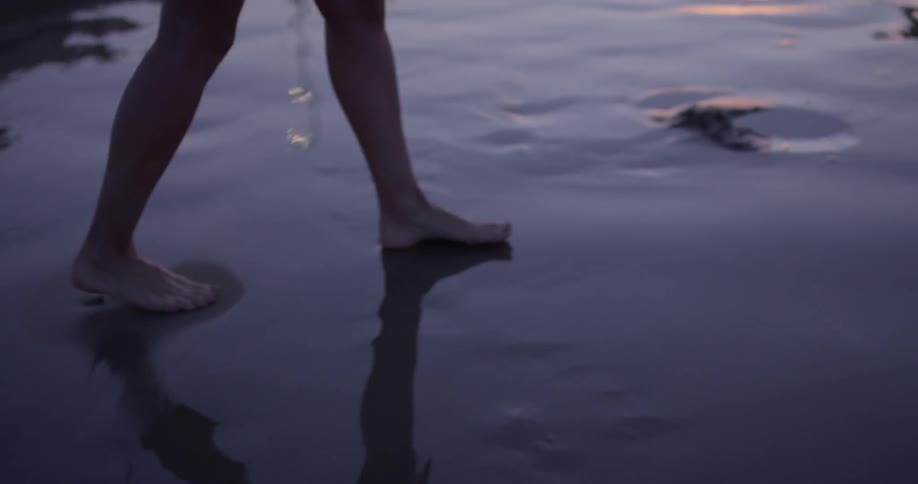 A person walks through wet sand