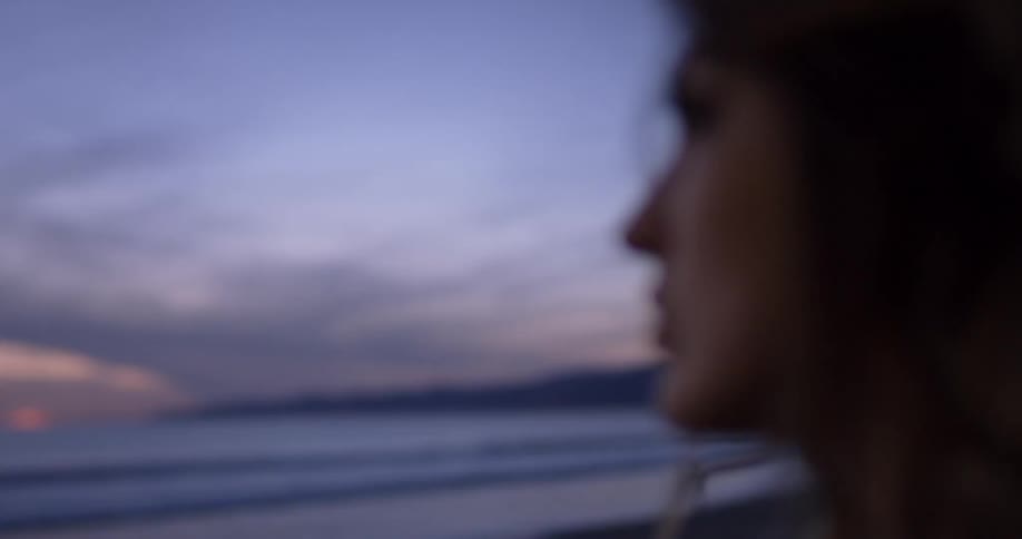 A woman stares at the ocean during sunset