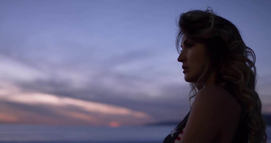 A woman standing on the beach staring at the ocean
